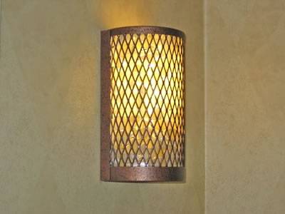 Brass color decorative expanded metal mesh on the wall covering the lamp.