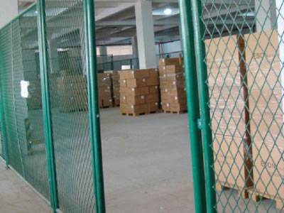Green expanded metal mesh is surrounding an area with several cartons in it.
