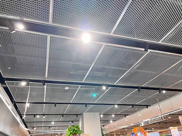 The ceiling of the shopping mall uses decorative expanded metal mesh to cover the pipes.