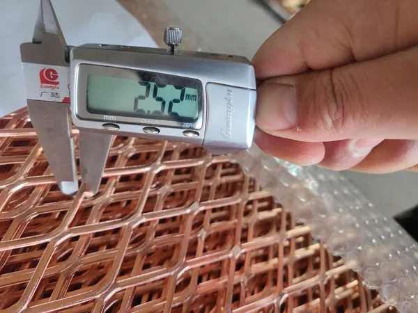 Worker measuring the strand width of the expanded copper mesh with a vernier caliper as 2.52 mm