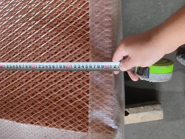 Worker measuring the width of the expanded copper mesh with a tape measure as 201.5 cm