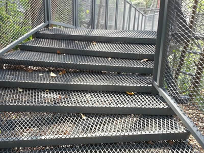 Expanded metal as stair treads on a bridge in the dense forest.