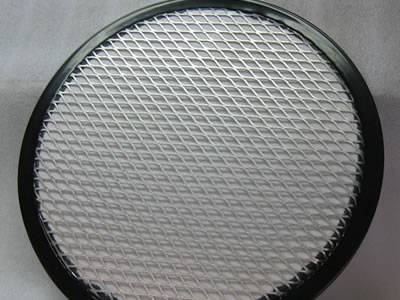 A piece of round filter element with black edge and expanded metal mesh supports.