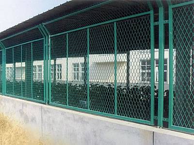 Des clôtures de sécurité en métal agrandi vert sont installées sur le mur du parking.