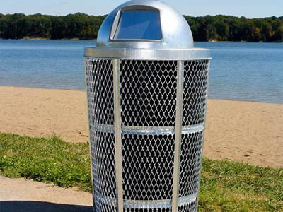 A galvanized expanded metal can is standing beside the beach.